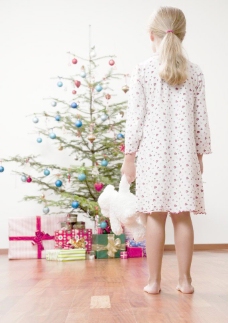 圣诞女孩拿玩具熊看礼盒圣诞树的小女孩图片